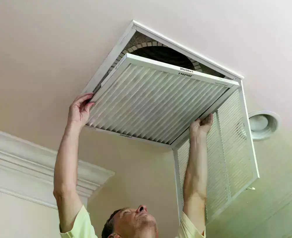 62df7c5eaac98f5da382181d senior male reaching up open filter holder air conditioning filter ceiling 1