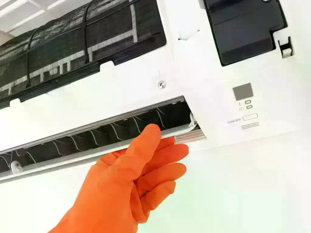 Indoor airconditioner being cleaned by person wearing orange gloves