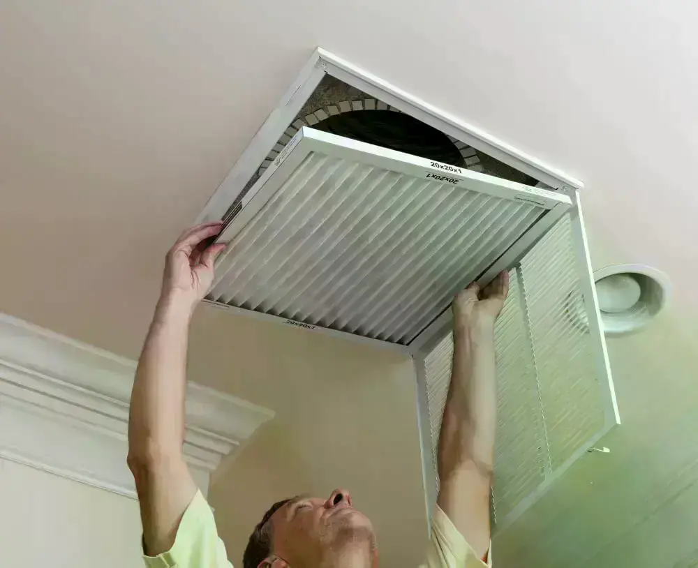 62df7c5eaac98f5da382181d senior male reaching up open filter holder air conditioning filter ceiling 1